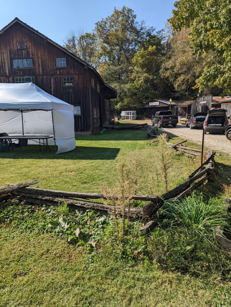 despaired split rail fence with white tent and old barn in background